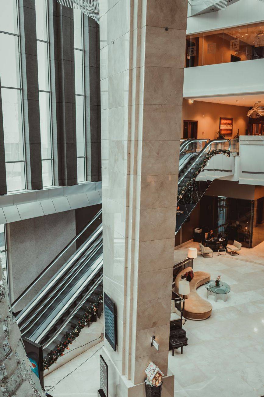 Modern hotel lobby featuring stylish escalators and festive decor.