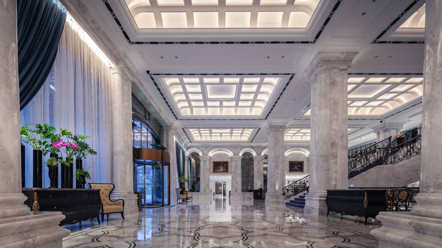 Elegant hotel lobby featuring grand marble columns, high ceiling, and decorative elements in a sophisticated design.