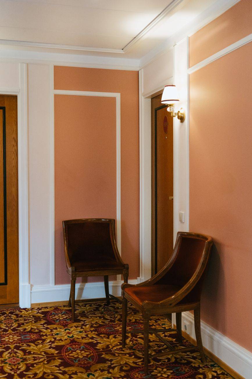 Stylish corner of a hotel hallway showcasing two chairs and vintage decor.