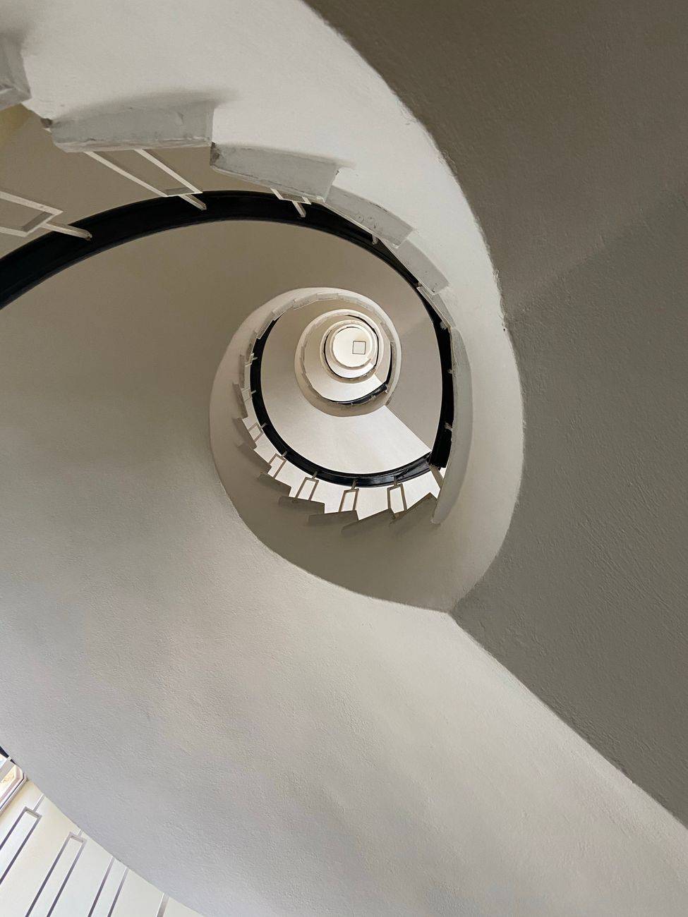 Artistic view of a spiral staircase with white railings.
