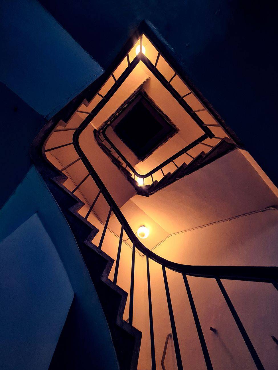 Captivating view of a spiral staircase illuminated at night with warm lighting, creating an abstract visual.