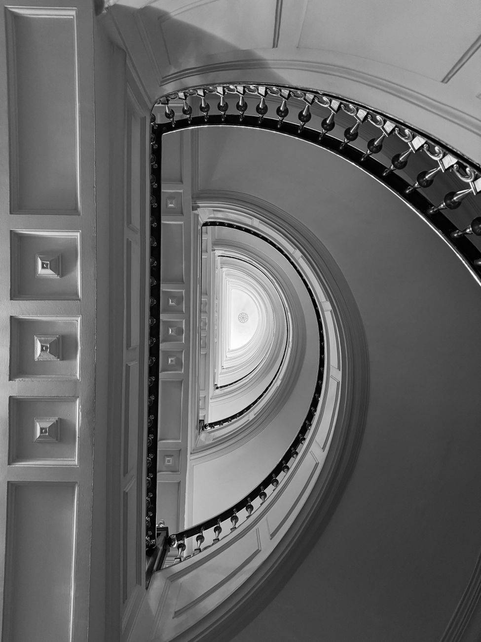 Artistic black and white shot of a spiral staircase in Madrid, showcasing elegant architectural design.