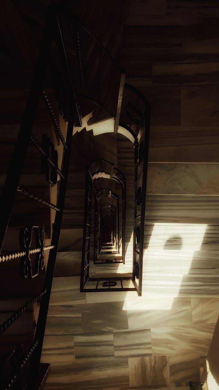 A mesmerizing view down a spiral staircase with dramatic light and shadows.