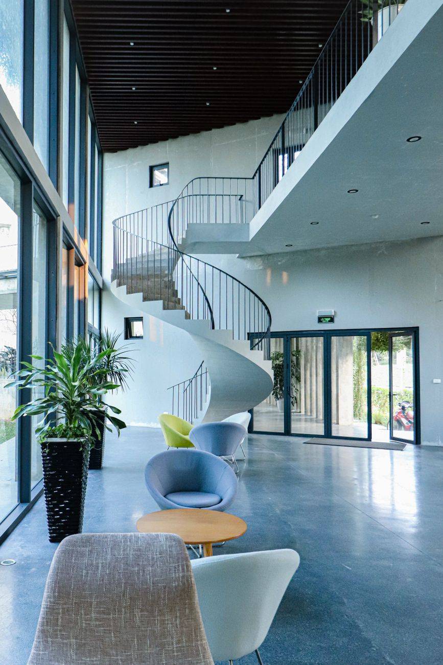Spacious hotel lobby featuring a unique spiral staircase and modern furniture.