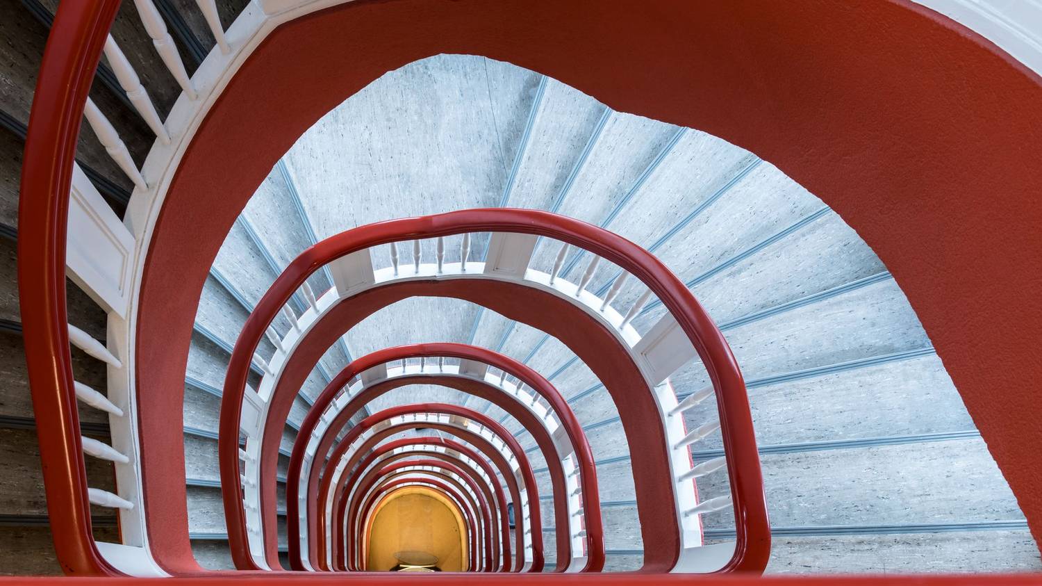 Elegant spiral staircase with red railings creates architectural intrigue in Hamburg.