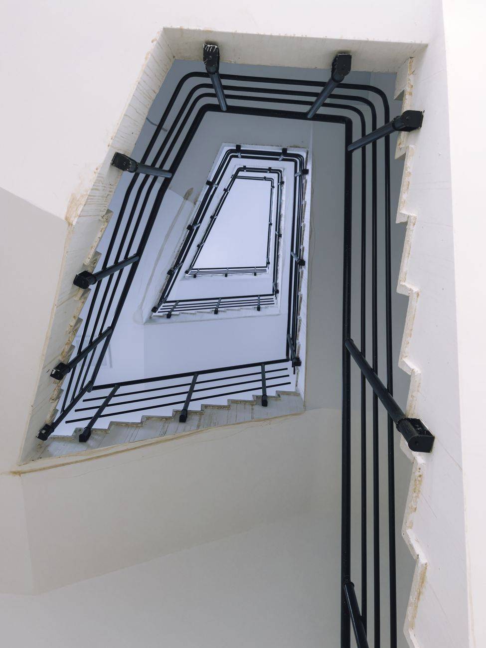 A striking perspective of a spiral staircase featuring modern black railings in an abstract geometric design.