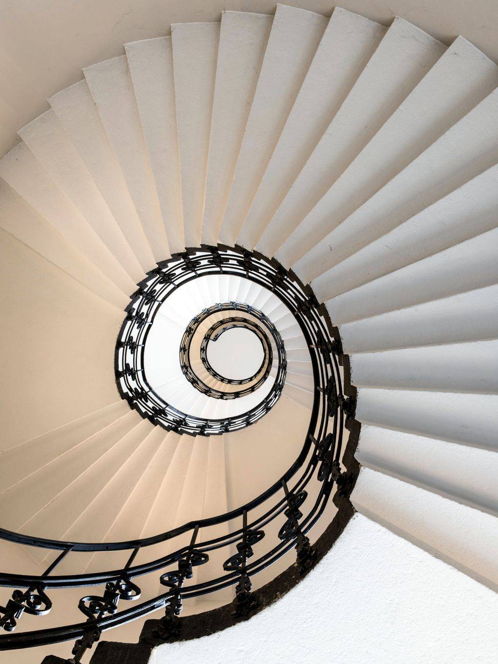 Ornate spiral staircase in Hamburg viewed from above, showcasing intricate design.