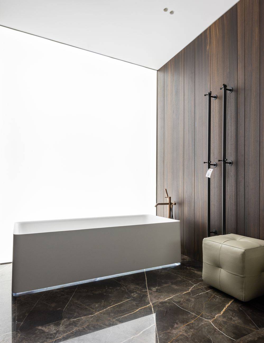 Interior design of spacious modern bathroom with big tub and leather pouf on ceramic tiled floor