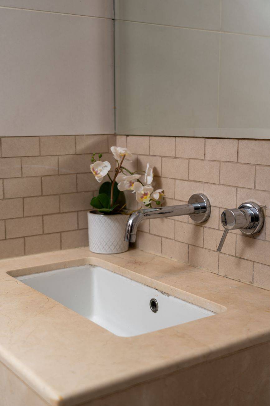 Stylish bathroom sink with chrome faucet and orchid decor in Dubai home.
