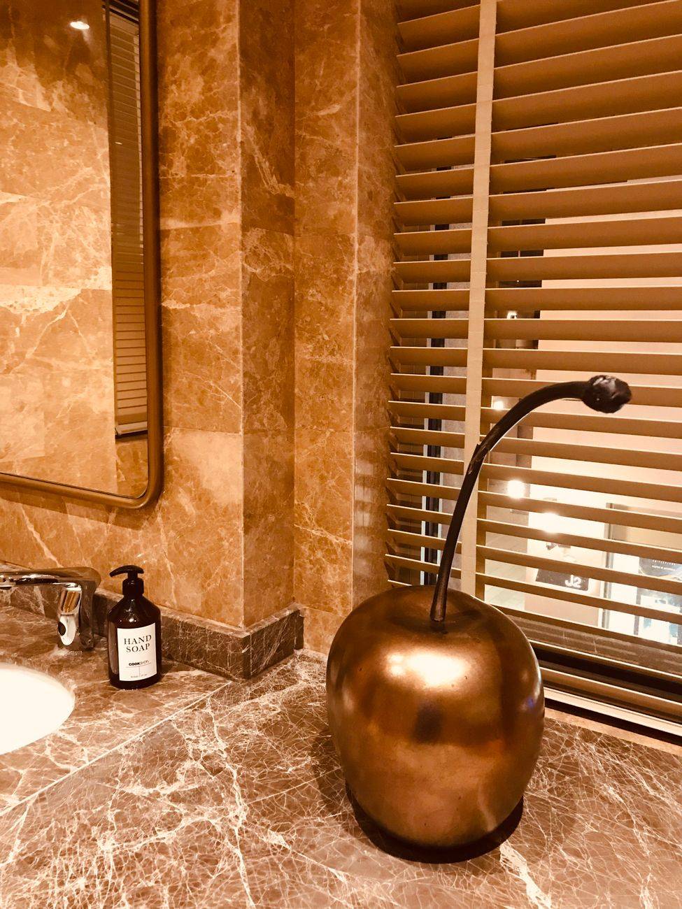 Luxurious marble bathroom with a golden apple sculpture and window blinds, İstanbul, Turkey.