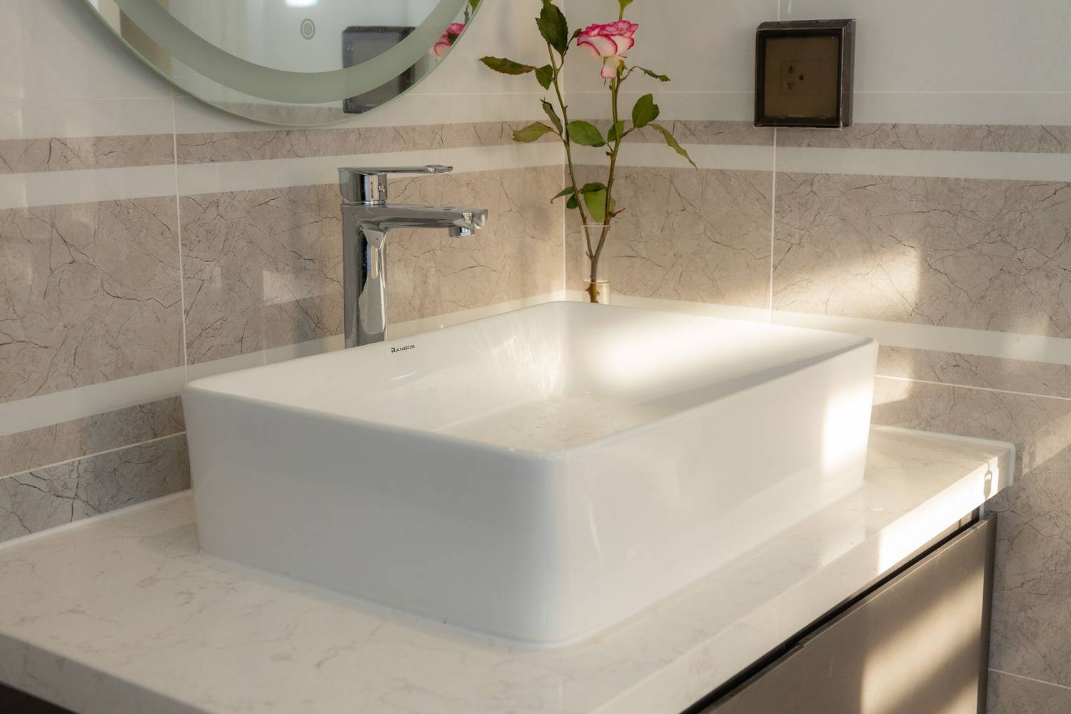 Elegant white sink in a modern bathroom with a pink rose decoration. Minimalist design with a touch of nature.