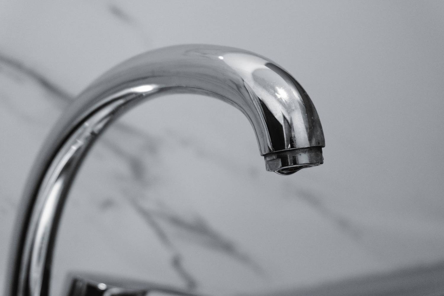 Close-up of a chrome faucet with a marble background, highlighting modern interior design.
