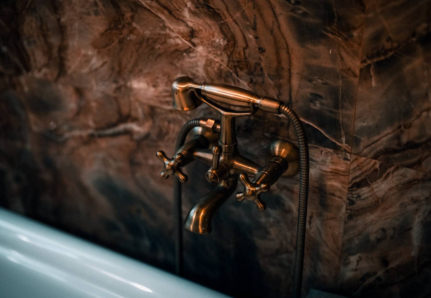 Elegant brass faucet fixture with a luxurious marble wall background.