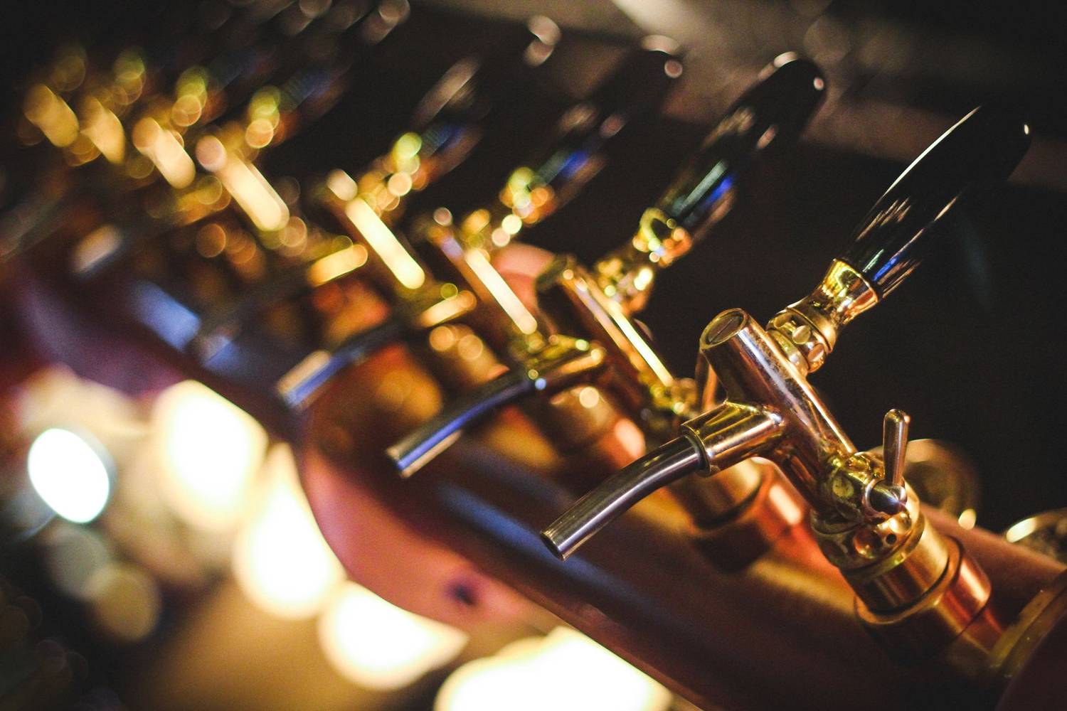 A close-up view of shiny golden beer taps in a bar setting, highlighting luxury and indulgence.
