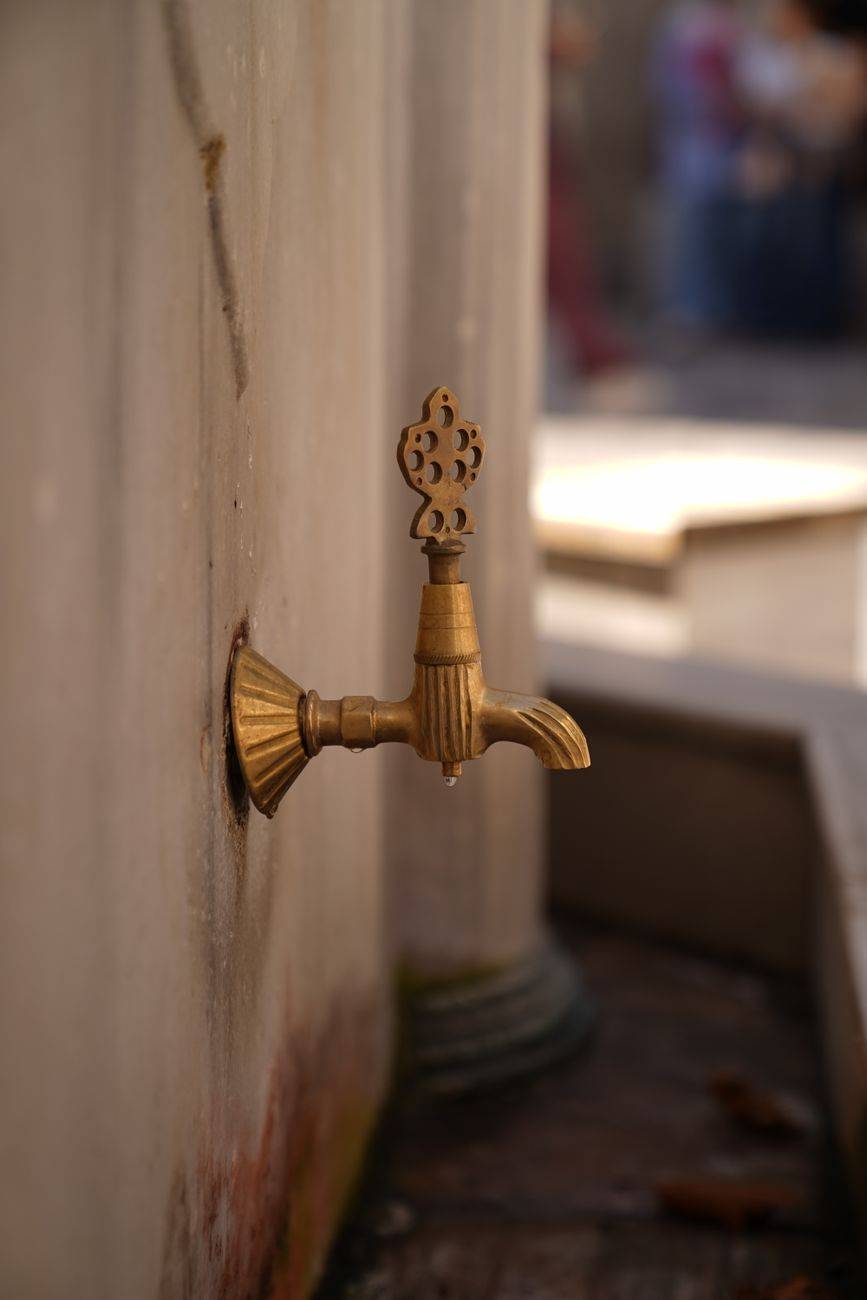 Close-up of an ornate brass tap against a stone wall in historic İstanbul.