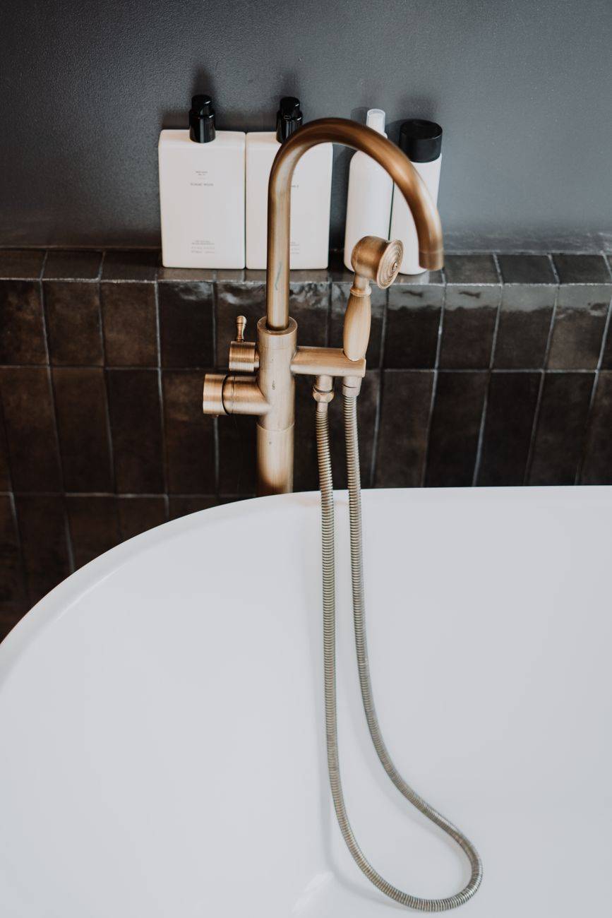 Elegant bathroom featuring a gold faucet and modern accessories on a dark tile background.