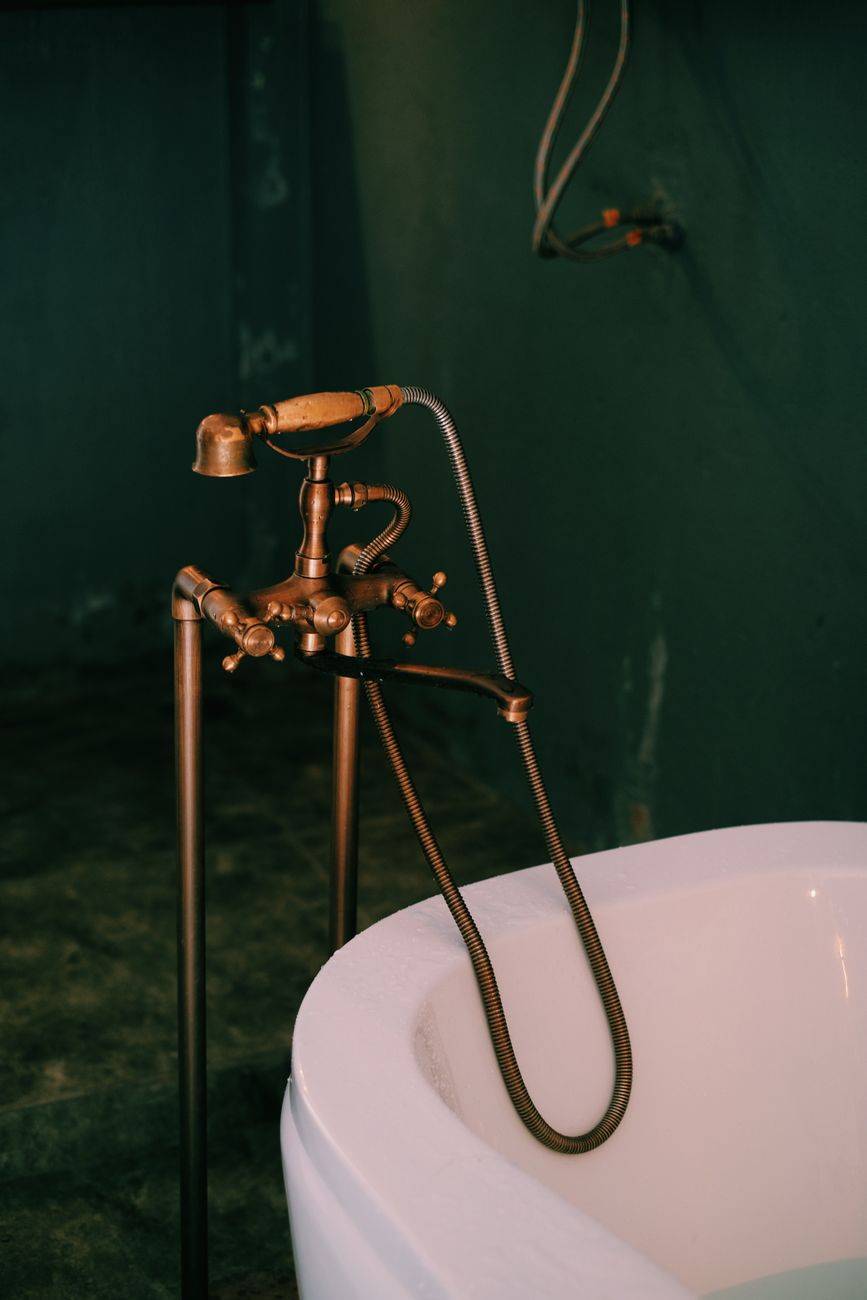 Vintage brass faucet and bathtub in dimly lit bathroom. Stylish and classic design.