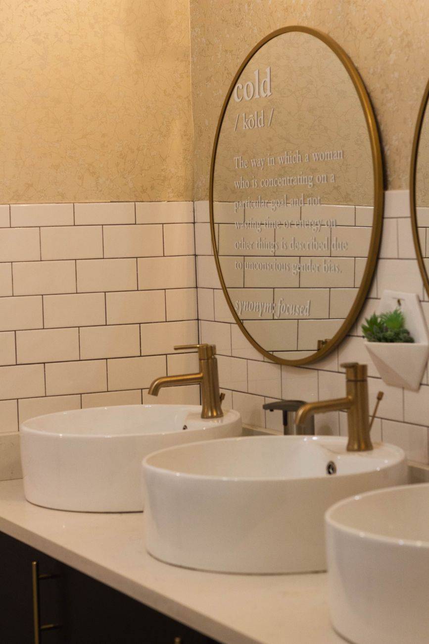 Sleek modern bathroom featuring gold faucets and white sinks with a stylish mirror.