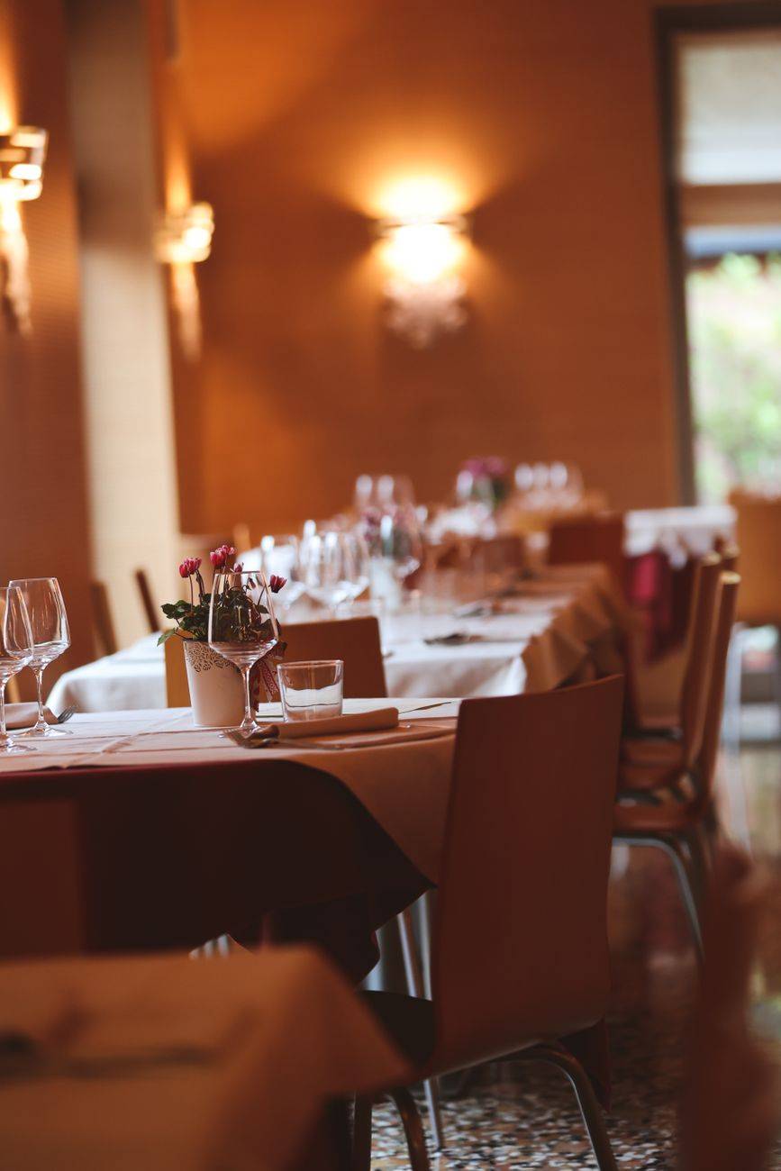 A warmly lit restaurant interior showcasing elegantly arranged dining tables and chairs.