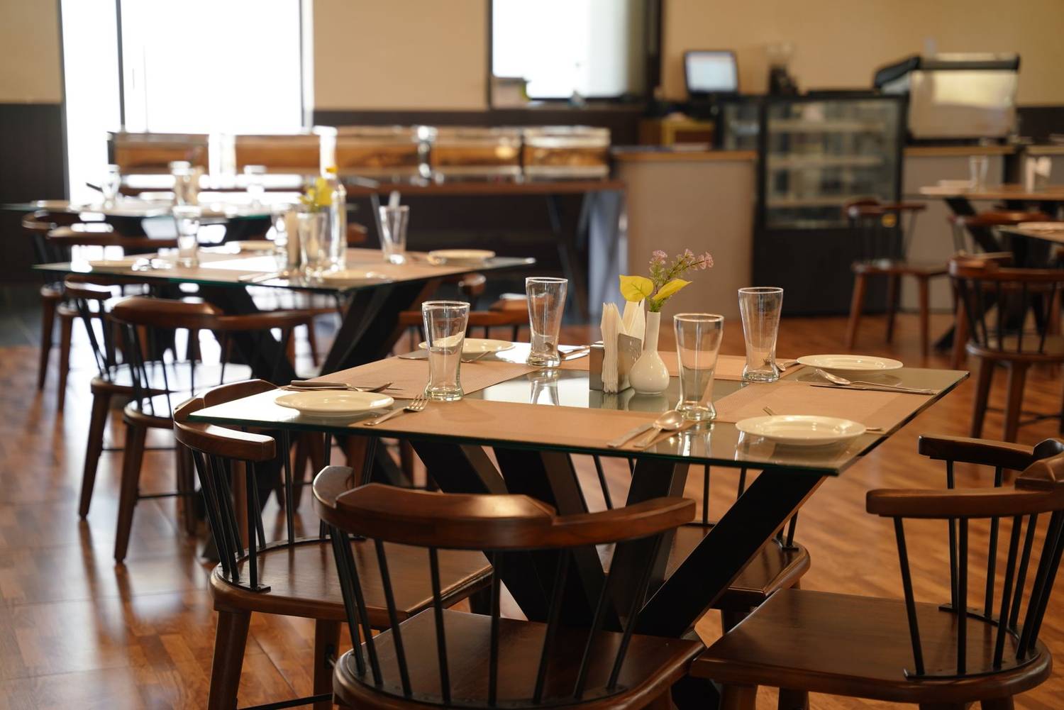 Spacious modern restaurant interior with elegant table settings and wooden decor, perfect for dining.