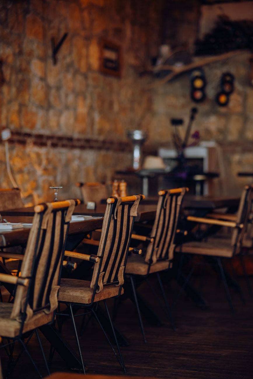 Rustic restaurant interior with empty wooden chairs set against a stone wall, creating a cozy dining atmosphere.