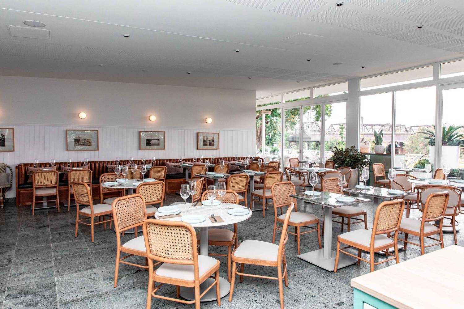 Elegant dining area with natural light, wooden chairs, and modern decor in a chic restaurant setting.