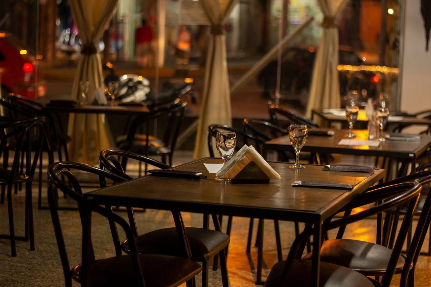Warmly lit restaurant interior with set tables, wineglasses, and napkins.