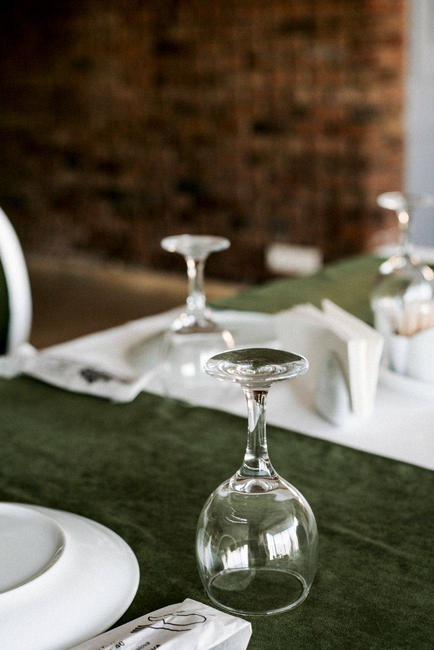 Upside-down wine glasses on a green tablecloth add elegance to a dinner table setting.
