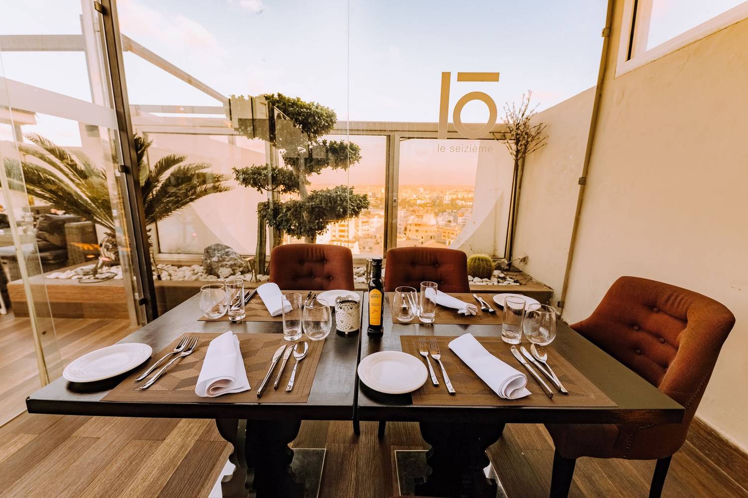 Luxurious dining setup in a rooftop restaurant overlooking the cityscape at sunset.