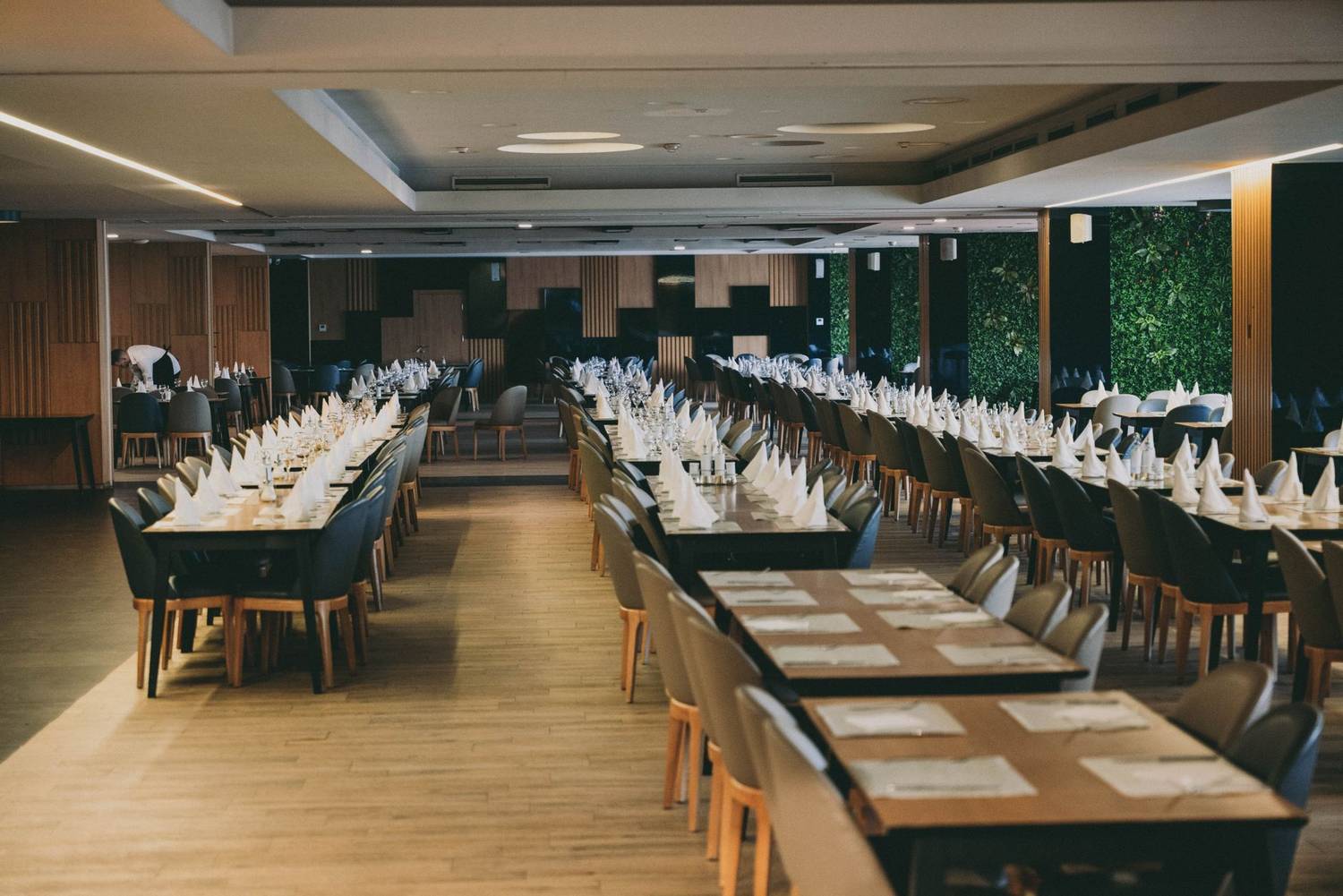 Spacious hotel restaurant interior with neatly arranged formal table settings ready for a grand event.