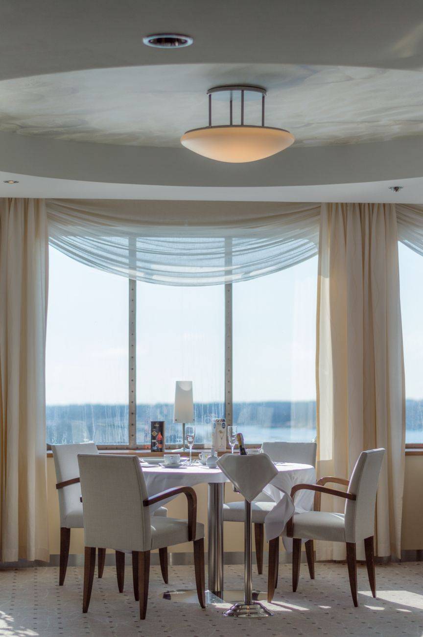Luxurious dining setup with white chairs and panoramic window view for an elegant dining experience.