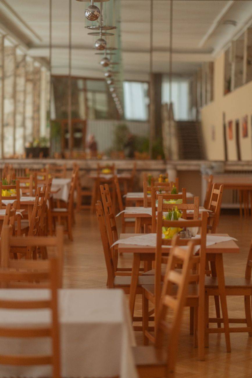 Spacious wooden interior of a hotel dining area with neatly arranged tables and chairs.