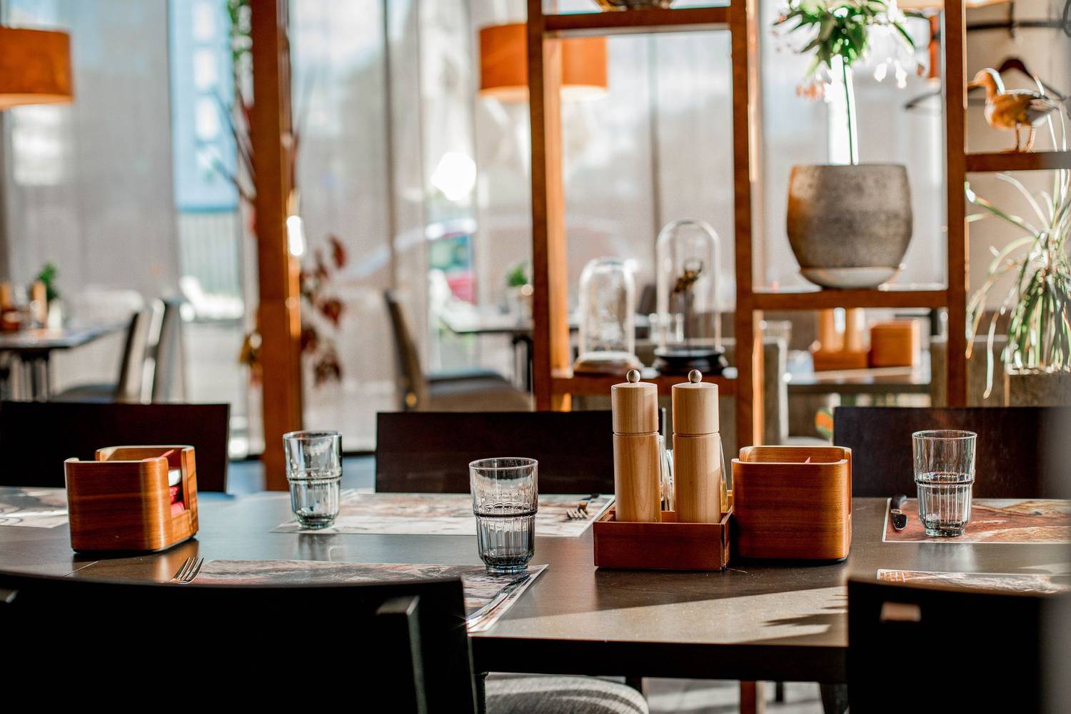 Elegant restaurant interior with sunlit tables and modern decor, perfect for dining.