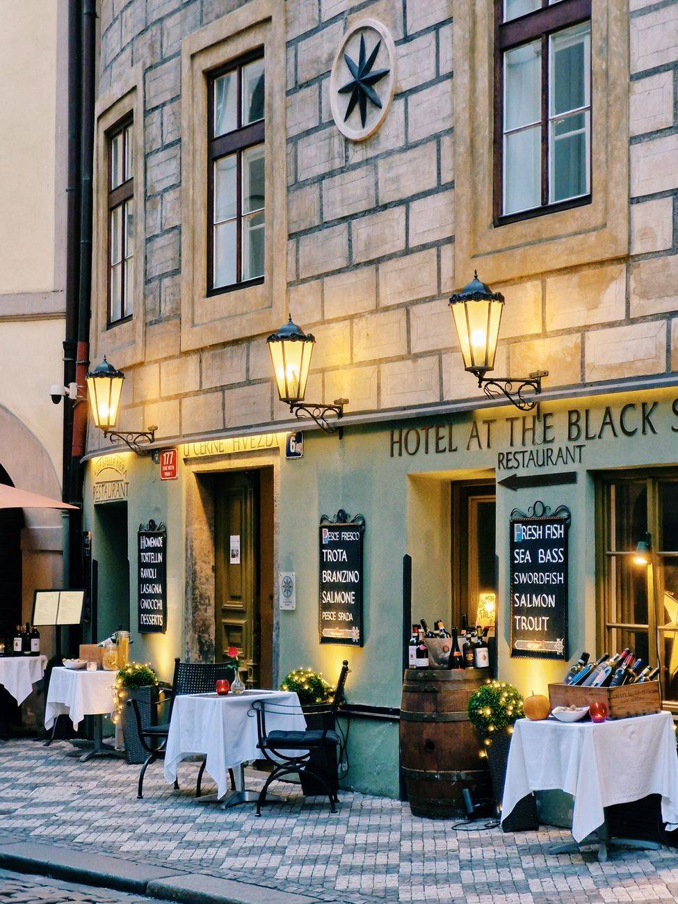 Evening view of a cozy restaurant facade in Prague's historic center, offering seafood dining.
