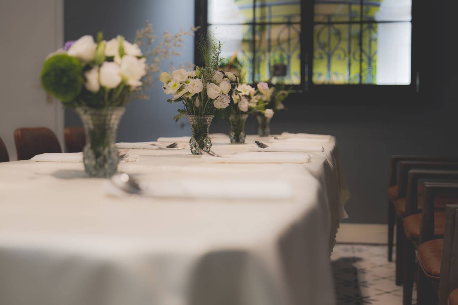 A luxurious dining table setup featuring elegant white tablecloths and beautiful floral arrangements in a sophisticated hotel interior.