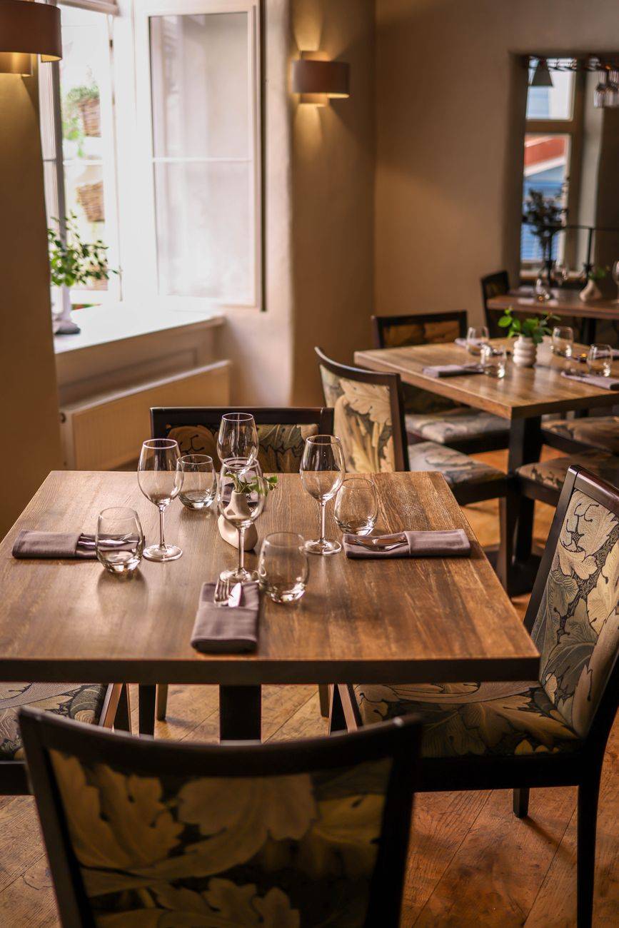 Cozy dining room featuring elegant wooden tables set with glassware and napkins.