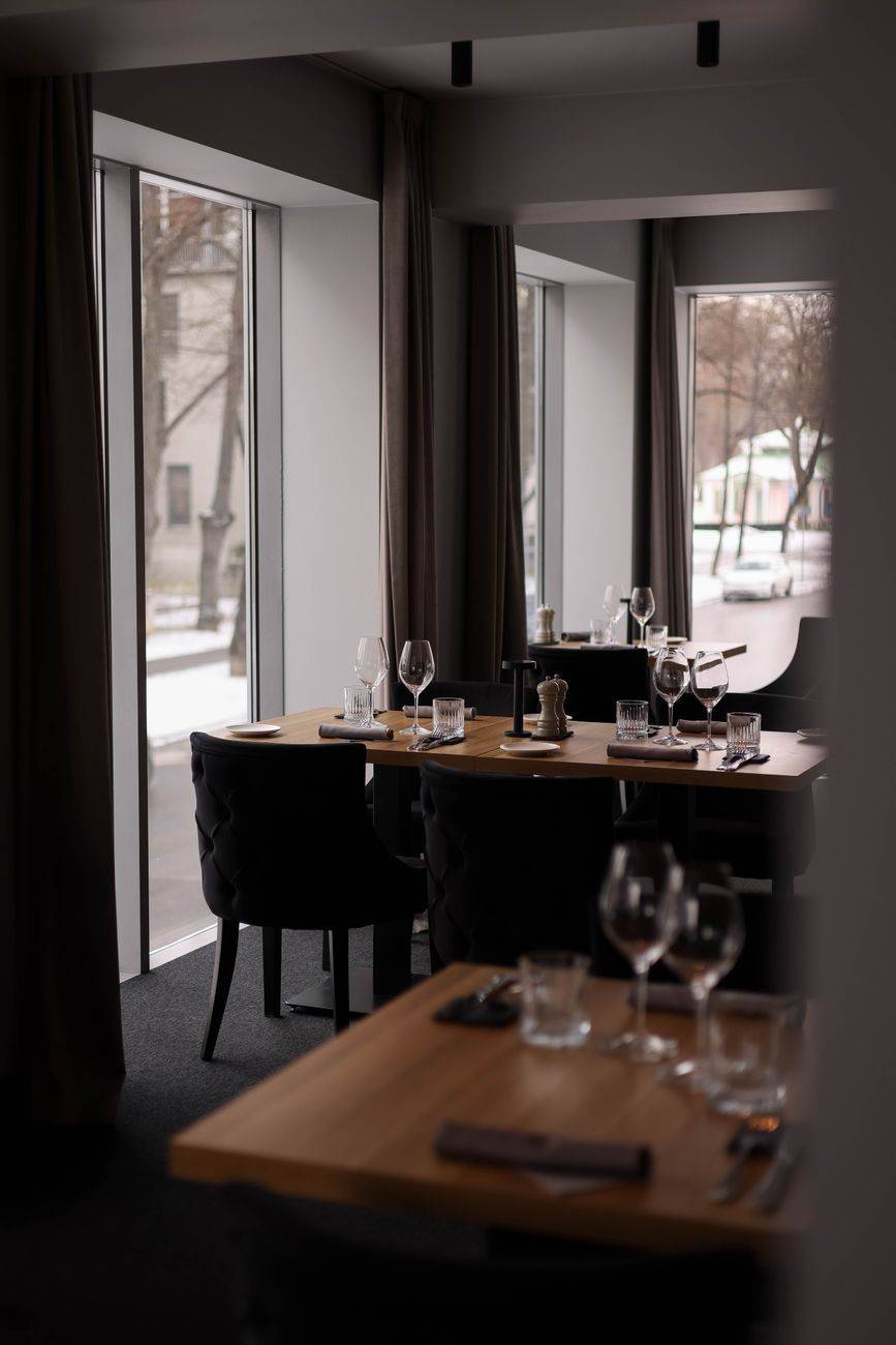 Modern dining room with elegant table settings and large windows providing natural light.