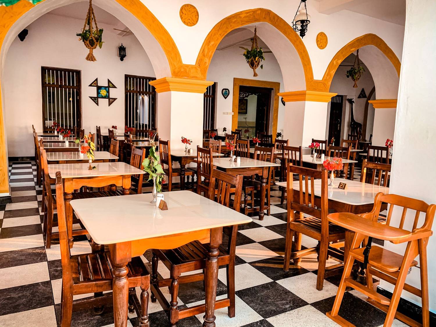 Elegant dining area with classic wooden chairs, checkered floor, and decorative arches.