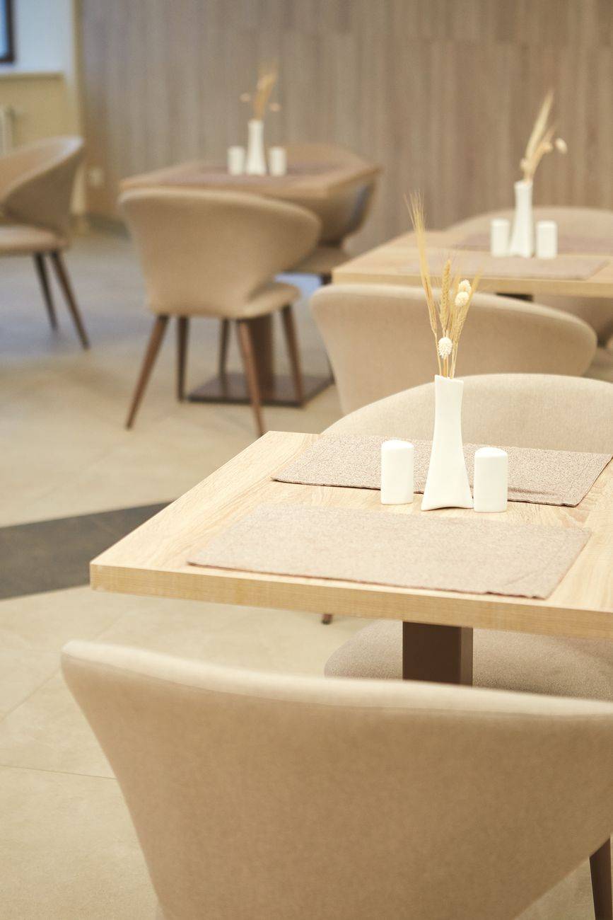 Sophisticated restaurant dining area with beige chairs and wooden tables, exuding minimalist elegance.