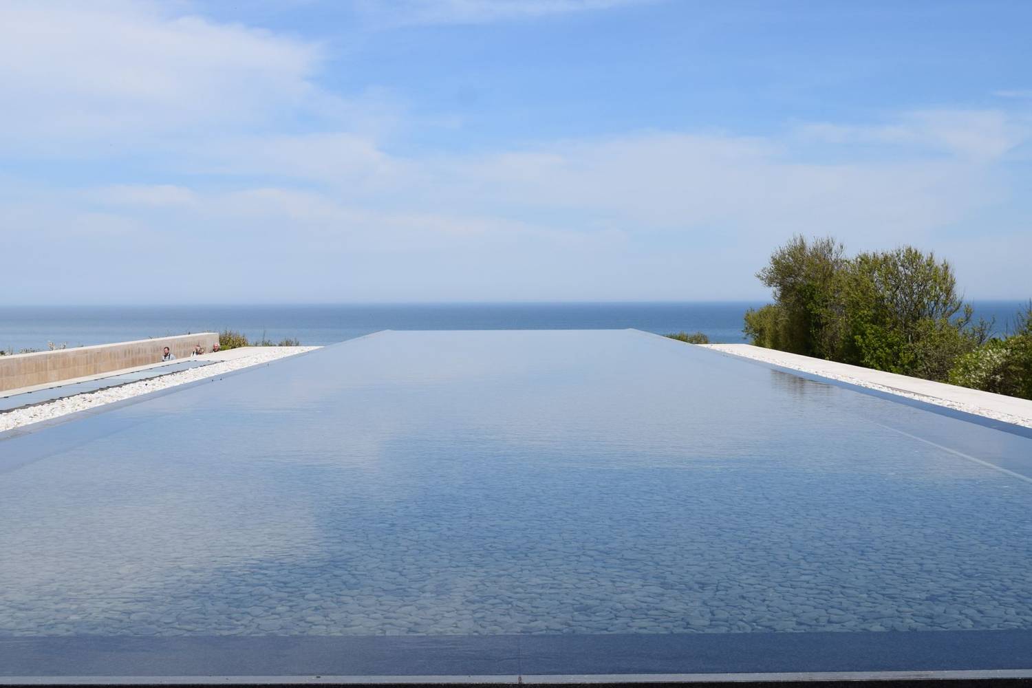 Tranquil infinity pool blending with the ocean horizon under a clear blue sky.