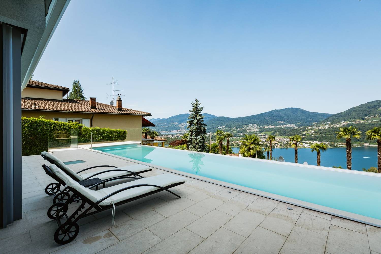Elegant lakeside infinity pool with stunning mountain and water views, perfect for relaxation and summer leisure.