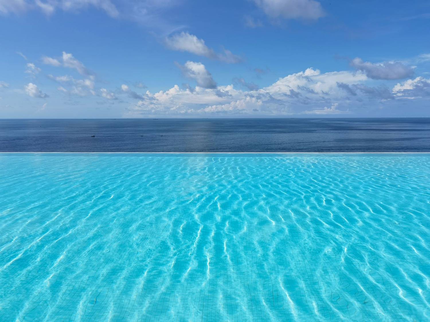 Serene infinity pool blending with ocean horizon under a clear blue sky.