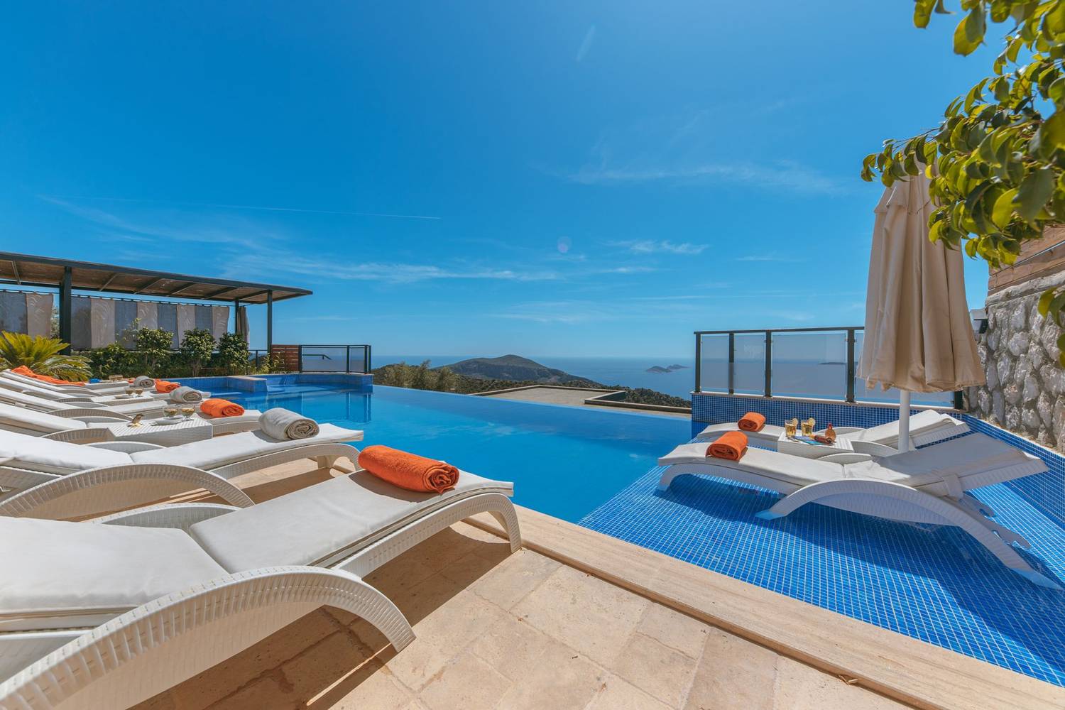 Relax by a stunning infinity pool with ocean views and sun loungers in a luxurious resort setting.