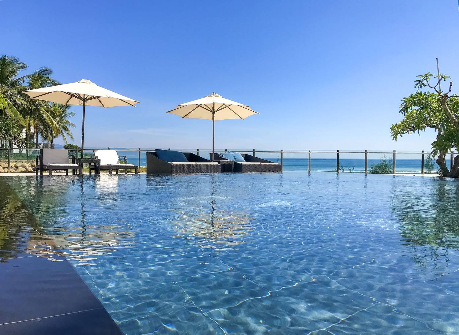 Idyllic poolside scene at a luxury resort with umbrellas and ocean view.