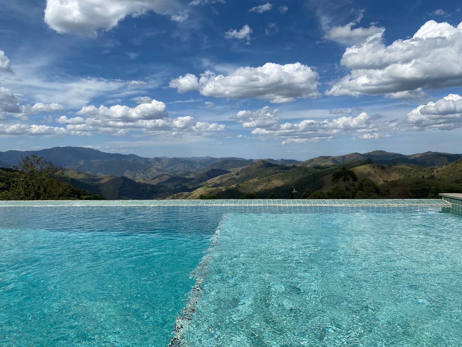 Stunning infinity pool with panoramic mountain views under a bright sky.