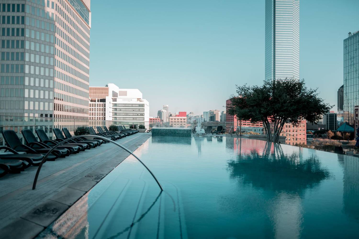 Rooftop infinity pool with city skyline and lounge chairs offering a tranquil escape.