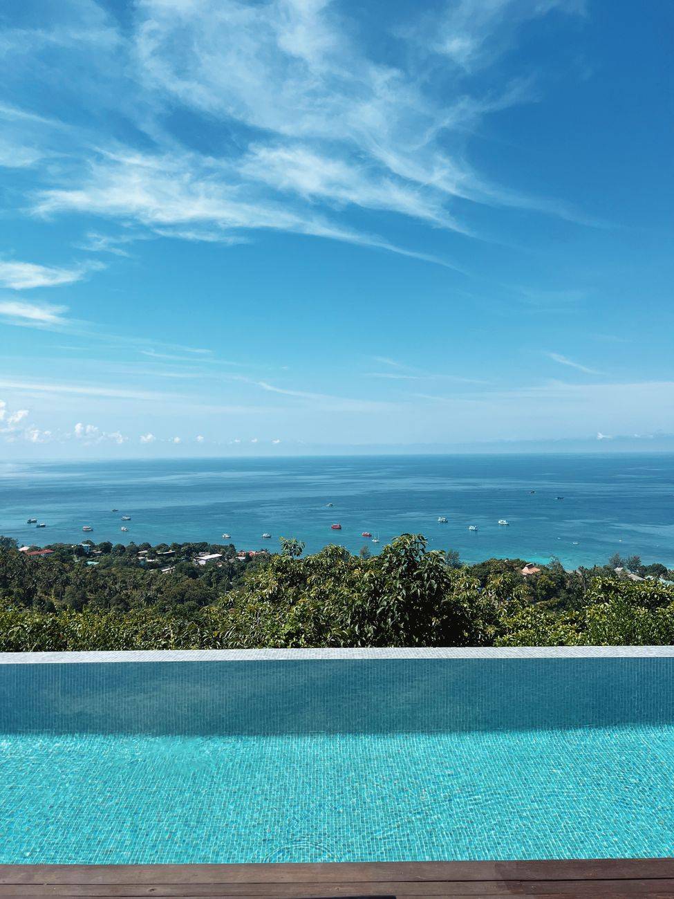 Serene infinity pool with panoramic ocean view under clear sky, perfect for relaxation and vacations.