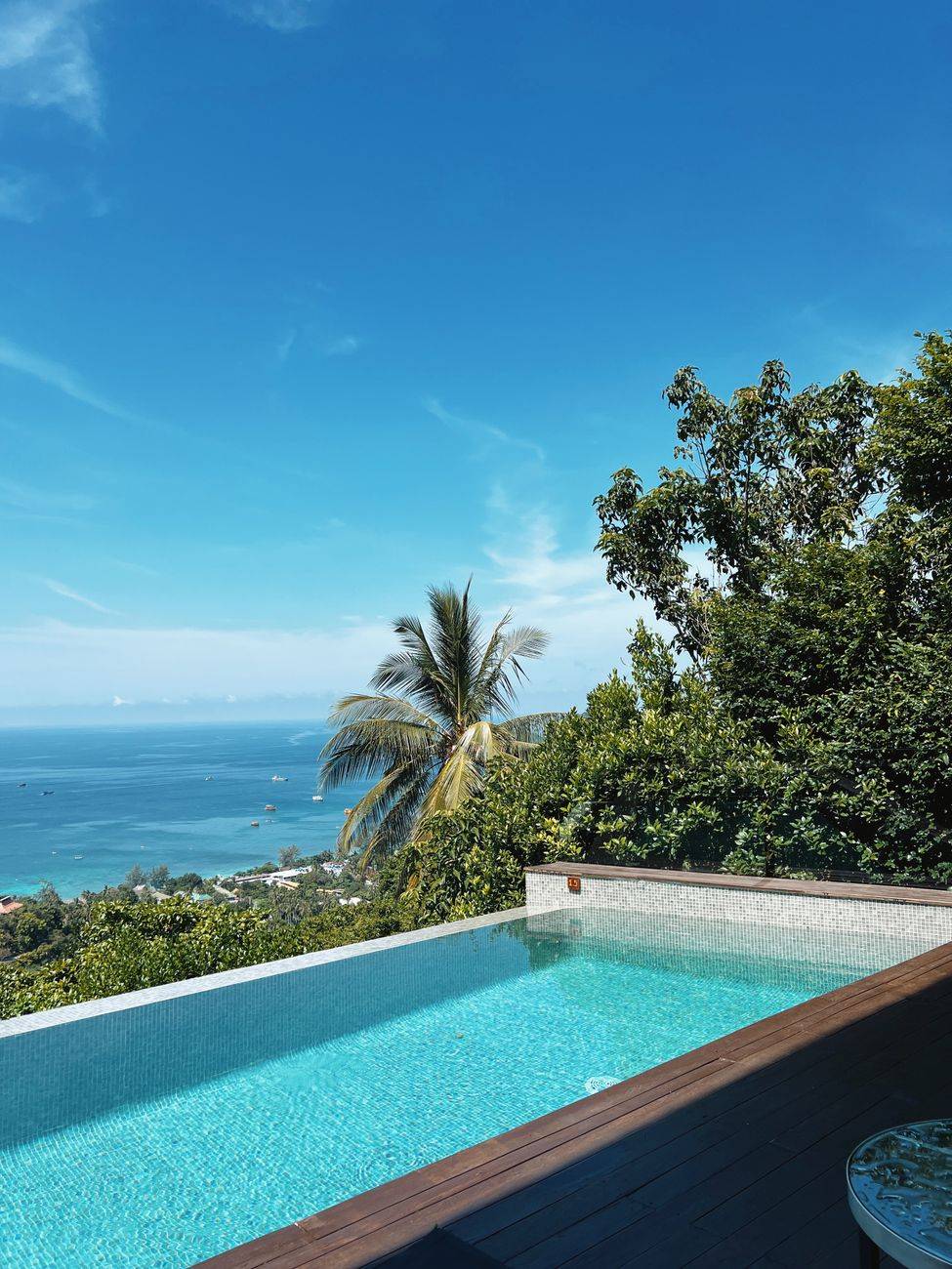 Infinity pool with ocean view surrounded by lush greenery, ideal for tropical vacations.