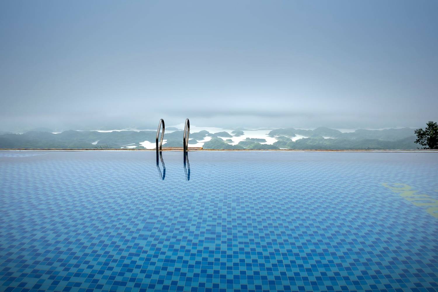 Infinity pool with mountain view and misty horizon offers tranquil escape.