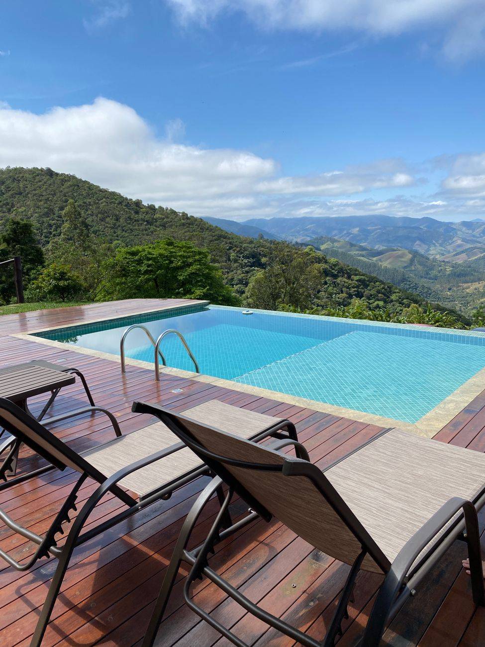 Infinity pool with deck chairs overlooking stunning mountains in São Francisco Xavier, Brazil.